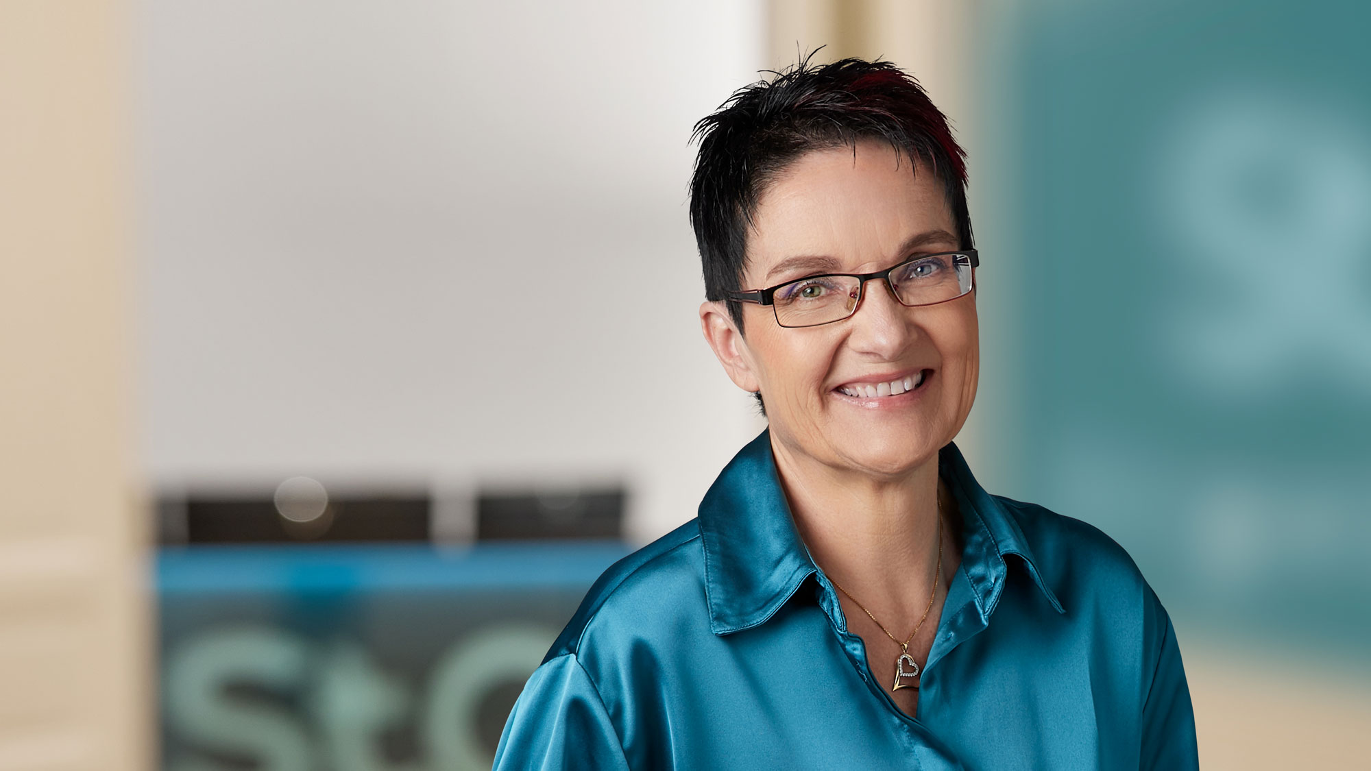 Portr&auml;t einer l&auml;chelnden Person mit Brille und blauem Hemd.